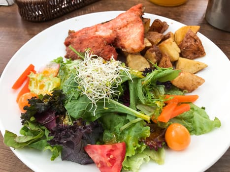 Grilled salmon fillet served with roasted potato wedges and a vibrant mixed green salad, showcasing a healthy and delicious meal in cusco, peru