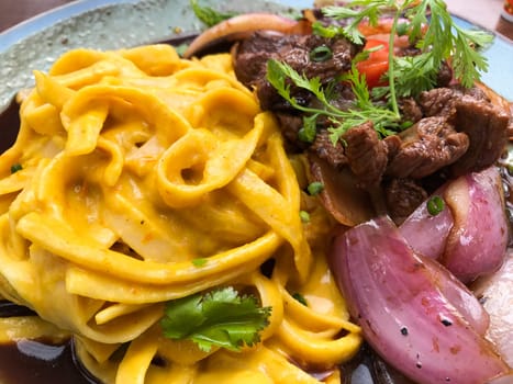 Delicious lomo saltado, peruvian beef stir fry with red onions and tomatoes, served with tallarines a la huancaina, pasta with creamy, spicy aji amarillo sauce
