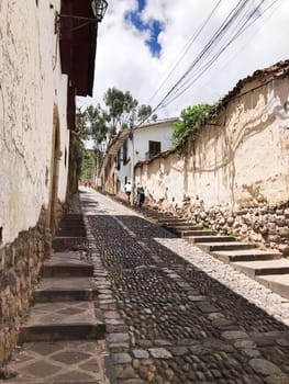 Traditional cobblestone street leading uphill in the historic city of cusco, peru, showcasing ancient inca architecture