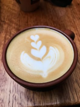Latte art coffee being served in a cozy cafe in cusco, peru, featuring a delicate leaf design