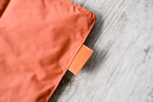 Orange pet bed with label on wooden floor, highlighting pet friendly materials and design