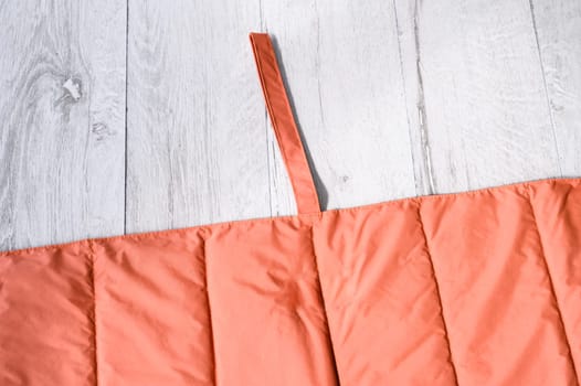 Orange waterproof and padded blanket or mat for pets like dogs and cats, folded on white wooden floor