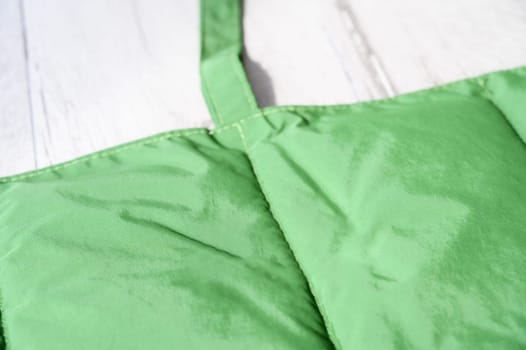 Close up of a green padded mat, designed for pets, placed on a white wooden table, emphasizing its softness and comfort