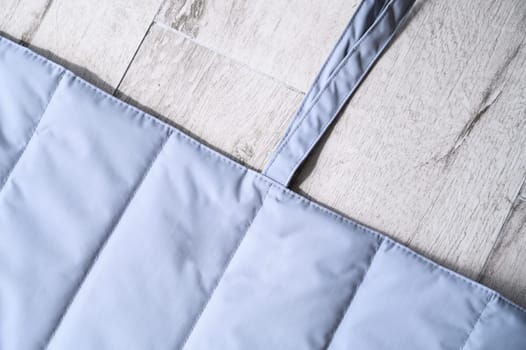 Quilted pet friendly carrier bag placed on wooden floor, perfect for transporting small dogs or cats