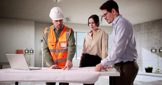 Engineer And Architect Inspecting Blueprint With Young Couple In Home.