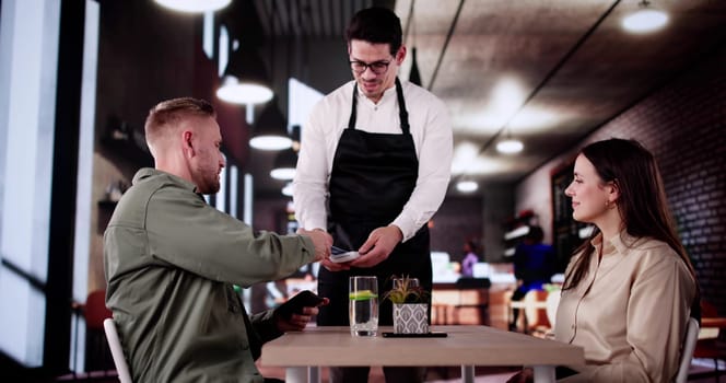 Young Couple Paying Their Bill Using Credit Card At Restaurant.