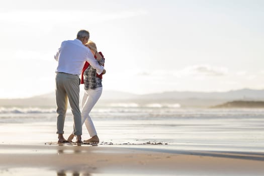 Happy retired couple enjoying a romantic dance on a beautiful beach at sunset