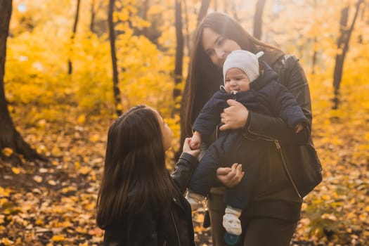 Mother holds baby in autumn forest. Family bonding and emotional connection through touch and nature.