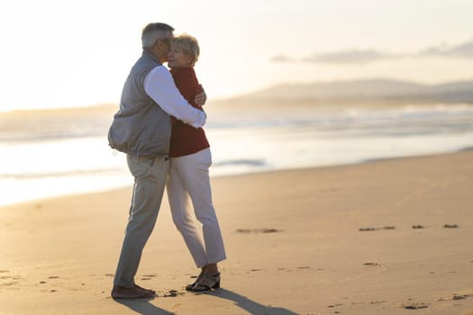 Elderly couple enjoying a romantic moment, embracing on the beach at sunset