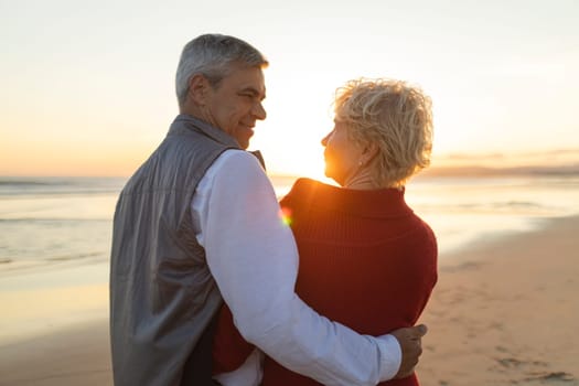 Retired couple embracing on beach at sunset, enjoying peaceful moment together