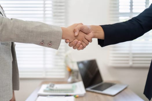 Two business professionals sealing a deal with a handshake, representing trust and collaboration in a modern office.