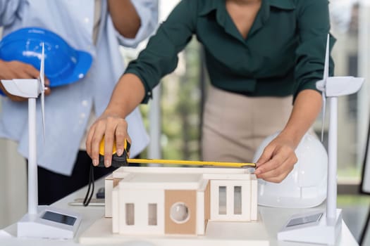 An engineer measuring a model for a sustainable architecture project, emphasizing teamwork and innovation in design.