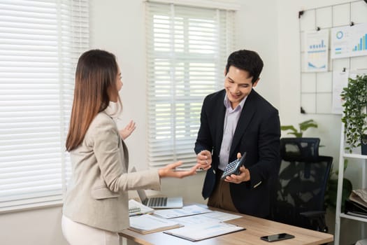 A woman gestures while discussing with a man, showcasing effective communication and teamwork in a bright, contemporary workspace.