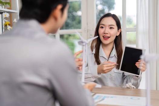 A woman presents sustainability ideas using a tablet during a business meeting, emphasizing ESG principles in an engaging discussion.