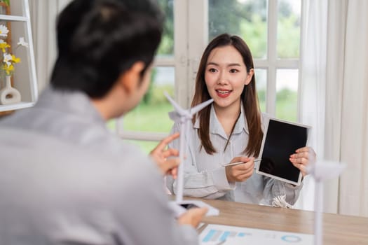 A professional woman discusses ESG initiatives using a tablet, highlighting renewable energy solutions in a business setting.