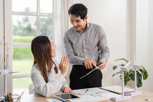 Two colleagues share ideas and insights on ESG practices while examining renewable energy models in a modern workspace.