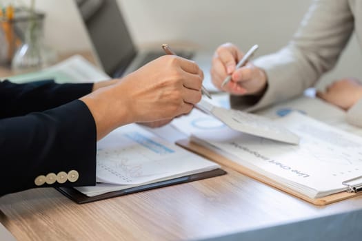 Close-up of hands during a financial discussion, highlighting collaboration and document analysis in a professional setting.