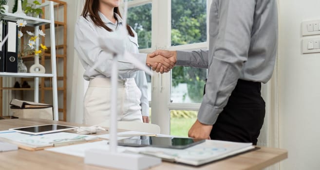 A handshake between two colleagues symbolizes partnership and commitment to ESG principles in a modern workspace.