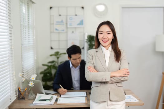 A confident businesswoman stands proudly in front of her colleague, showcasing leadership in a collaborative office environment.