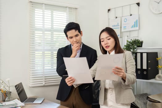 Two professionals analyze project documents, discussing strategies and insights in a bright, modern office space.