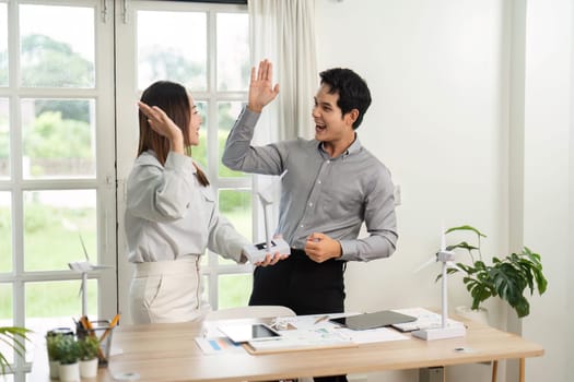 Two professionals express joy and excitement over their successful ESG project in a modern office setting.