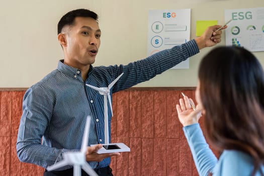 A man passionately presents wind turbine concepts to a woman, highlighting ESG principles in renewable energy.