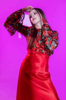 A stylish and fashionable model elegantly showcases a stunning outfit against a bright pink background