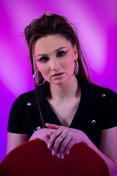 This is a striking artistic portrait of a young woman showcasing dramatic makeup against a vibrant background