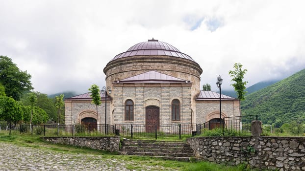 Three Saints Church, also known as The Round Temple, is situated amidst lush greenery and misty mountains in Shaki, Azerbaijan