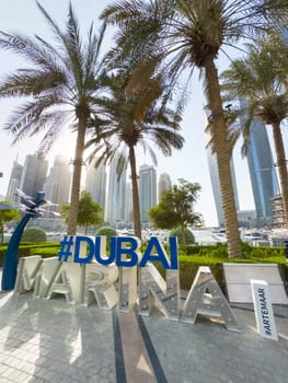 UAE, Dubai, 29 September 2024: Dubai Marina art object against the background of palm trees and skyscrapers on a clear sunny morning. High quality photo