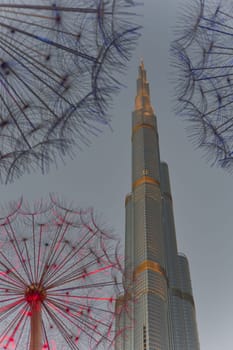 UAE, Dubai, 11 December 2024: The famous Burj Khalifa skyscraper through the art object metal dandelions at dusk, Dubai's sights during the incredible sunset sky, skyscrapers illuminated. High quality photo