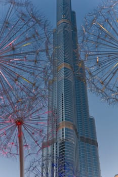 UAE, Dubai, 11 December 2024: The famous Burj Khalifa skyscraper through the art object metal dandelions at dusk, Dubai's sights during the incredible sunset sky, skyscrapers illuminated. High quality photo