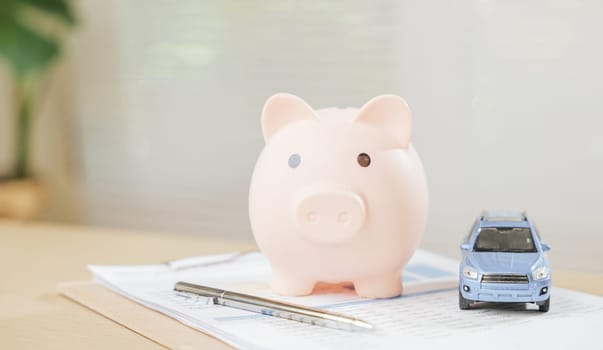 A car piggy bank with a pen and banking book symbolizes saving money, finance planning, and business growth. Highlights success, retirement savings, and insurance strategies for financial stability.