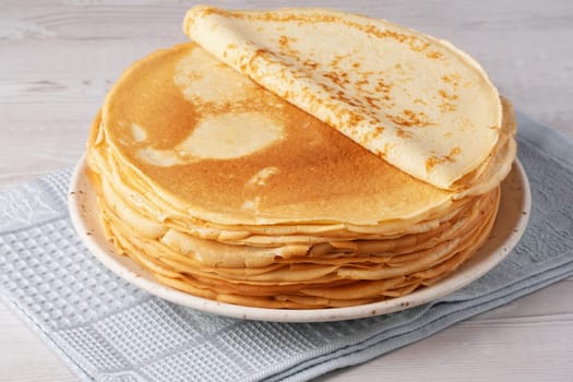 Thin pancakes on a wood table. Homemade crepes, tasty food. Staple of yeast pancakes, traditional for Russian pancake week (Shrove tide). Thin pancake with crispy crust.