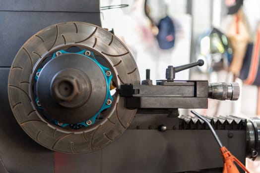 Car mechanic or serviceman disassembly and checking a disc brake and asbestos brake pads for fix and repair problem at car garage or repair shop