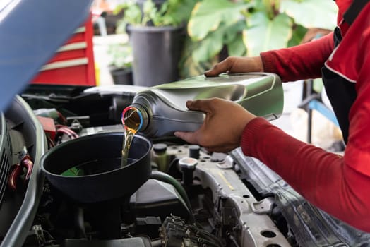 Car mechanic drain the old lubricant engine oil at car garage for changing the oil in a car engine