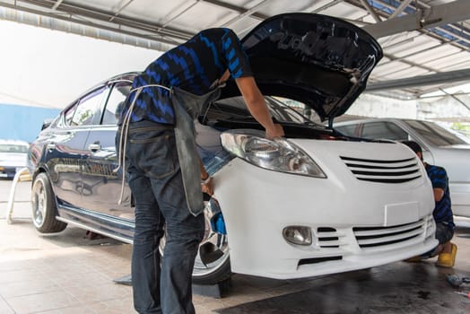 Denter or car mechanic serviceman check and fix body work and fiber bumper body part for fix and repair problem at car garage or repair shop