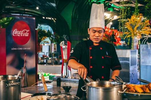 A Vietnamese chef cooks in the Asian buffet hall. Nha Trang, Vietnam - December 12, 2024