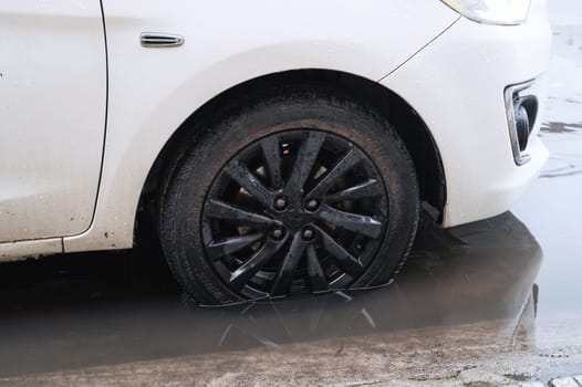 A close-up of the front wheel of a car that stands on the road after a flood, the concept of car insurance and car repair. Nha Trang, Vietnam - December 13, 2024.