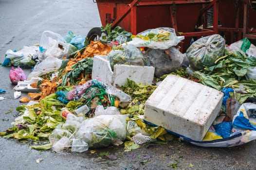 Close-up of a pile of junk and a dumpster next to overflowing dumpsters. Plastic bags, cardboard boxes, and organic waste. Nha Trang, Vietnam - December 13, 2024