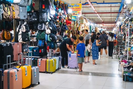 A lively passage of the indoor clothing market with suitcases, bags and other clothing items on display. Nha Trang, Vietnam - December 13, 2024
