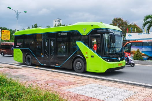 A green Vietnamese electric bus travels along the roads of Nha Trang. Nha Trang, Vietnam - December 16, 2024