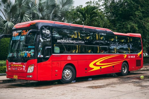 A red Asian SleepBus with recumbent seats is parked in the parking lot and waiting to board the flight. Nha Trang, Vietnam - December 16, 2024