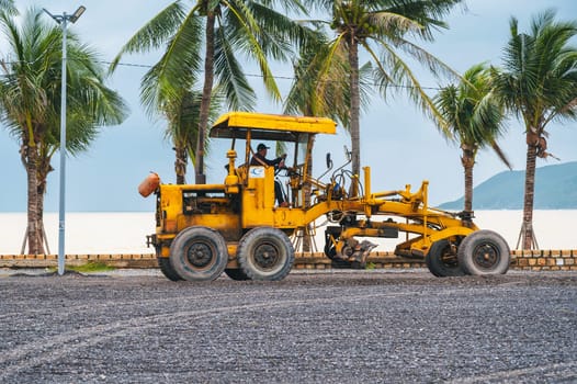 A construction site with a bulldozer on the seashore under palm trees. Nha Trang, Vietnam - December 16, 2024.