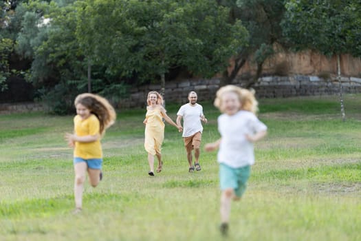 Parents holding hands and running with their children in a park
