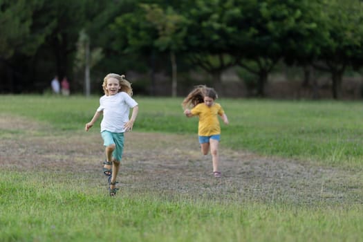 Two children running happily on the grass in a park, enjoying a sunny day outdoors