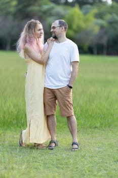 Couple holding hands and smiling while walking in a park, enjoying a romantic moment together surrounded by nature