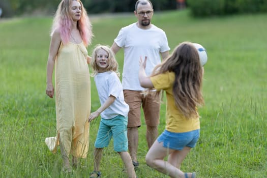 Family having fun playing ball together in a park on a summer day