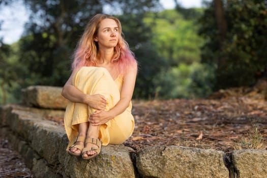 Young woman with pink hair enjoying a peaceful moment in nature, finding solace and introspection amidst the tranquil surroundings
