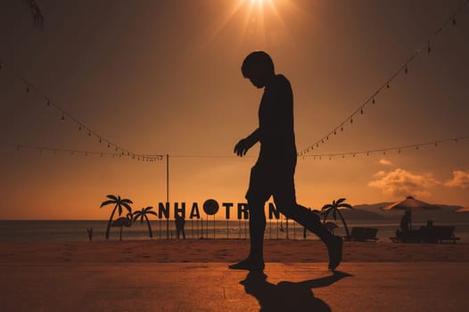 Silhouette of a Vietnamese man on embankment by the beach with the sea in the morning at sunrise in summer in Nha Trang, Vietnam